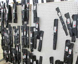 A pegboard wall with racks of lawn mower blades
